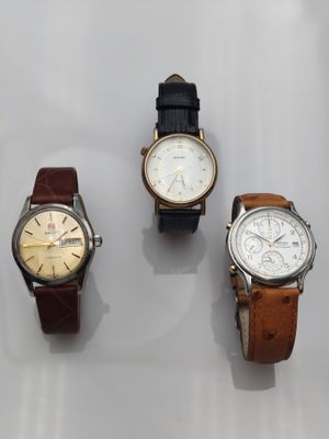 trois montres sont présentées sur une surface blanche avec un fond blanc