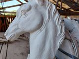 une statue représentant une tête de cheval posée sur une table en bois