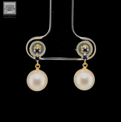 a close up of a pair of earrings with pearls on them
