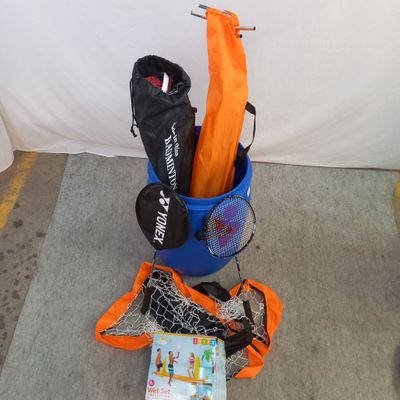 un seau bleu avec des parapluies orange et un livre posé par terre