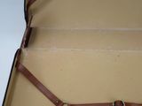 a brown suitcase with two handles and a strap