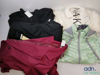 Plusieurs vestes et pantalons sont disposés sur une surface blanche