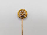 a close up of a gold and diamond broochle on a stick
