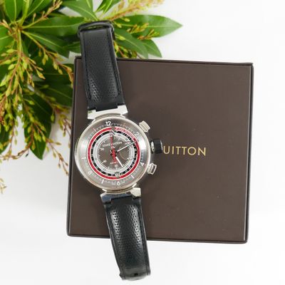 a close up of a watch sitting on top of a box next to a plant