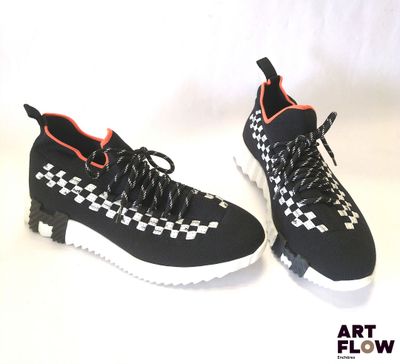 baskets à carreaux noirs et blancs avec des touches orange sur fond blanc