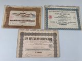 three old certificates are on display on a white surface