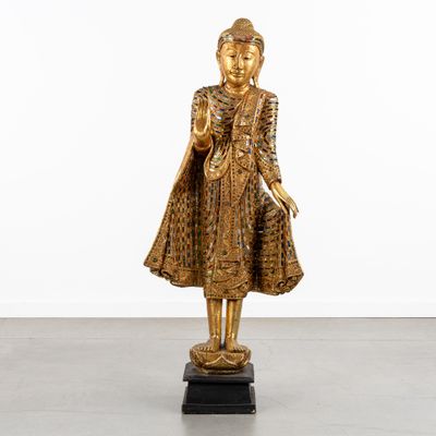 une statue en or représentant une femme en robe, debout sur un socle