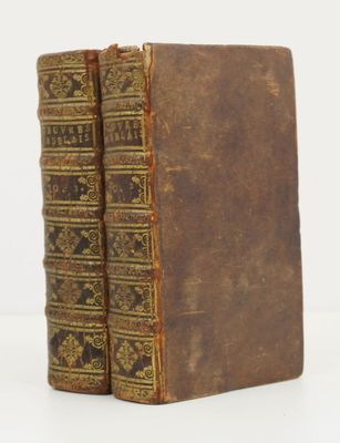 two old books sitting on top of each other on a white surface