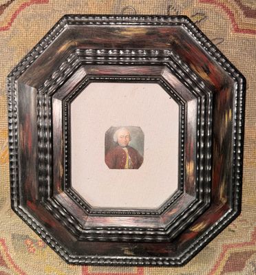 un vieux cadre contenant la photo d'un homme vêtu d'un manteau rouge