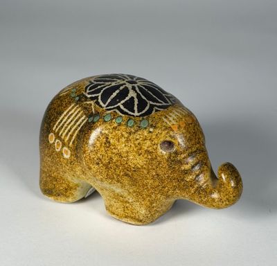 une figurine d'éléphant posée sur une surface blanche