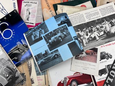 une pile de vieilles brochures automobiles posée sur une table