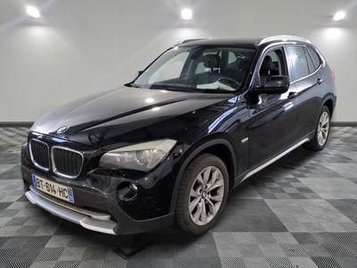 La BMW X1 est garée dans le garage, sur un sol à damier.