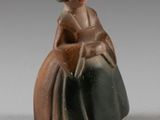 une figurine de femme assise sur une chaise