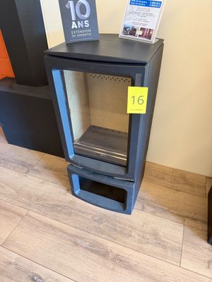 un poêle noir avec une porte vitrée, dans un coin de la pièce