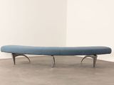 a blue bench sitting on top of a cement floor next to a white wall
