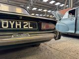 two old cars parked in a garage next to each other