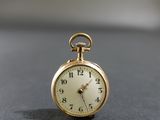 une petite montre de poche en or posée sur une table