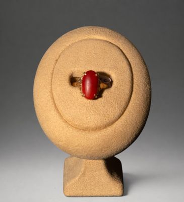 une image représentant une bague en pierre rouge posée sur un socle