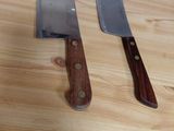 two knives sitting on a wooden table next to each other
