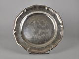 an antique silver plate on a stand on a gray background