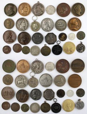 a large collection of old coins and medals on a white surface