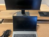 an open laptop computer sitting on top of a wooden desk next to a monitor