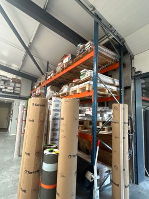 de nombreux rouleaux de papier posés sur une étagère dans un entrepôt