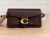 a small brown purse with a gold buckle on a wooden table