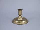 a small brass candle holder on a white surface
