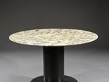 une table ronde en marbre avec un piètement noir et un piètement noir