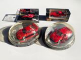 deux petites voitures rouges dans un bol en verre posé sur une table