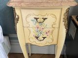 a small chest of drawers with flowers painted on it
