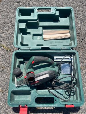 une mallette à outils verte posée par terre, contenant des outils