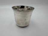 une vieille coupe en argent munie d'une anse, posée sur une surface blanche