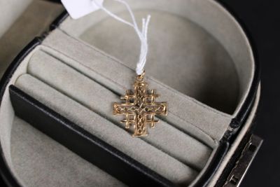 une croix en or montée sur une bague, dans un écrin