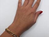woman ' s hand with red manicured nails and a gold chain bracelet