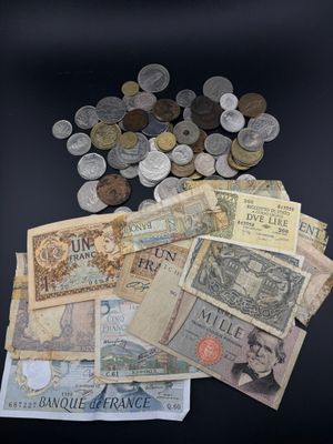 several different bank notes and coins on a black surface