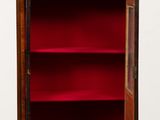 an old wooden cabinet with a red velvet door and shelves