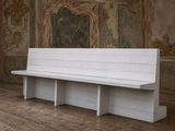 un banc blanc placé dans une pièce ornée d'une peinture murale