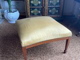 a yellow foot stool sitting on top of a carpeted floor next to a cabinet