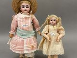 une paire de poupées en porcelaine représentant une fille et un garçon, vêtus de robes et coiffés de chapeaux
