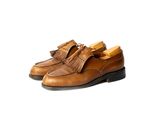 chaussures en cuir beige ornées de pompons sur fond blanc