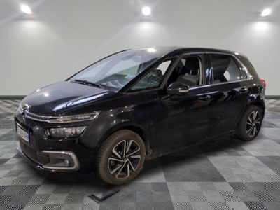 a black minivan parked on a checkered floor in a garage