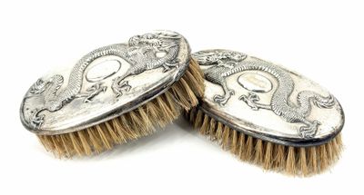 pair of antique silver plated brushes on a white background