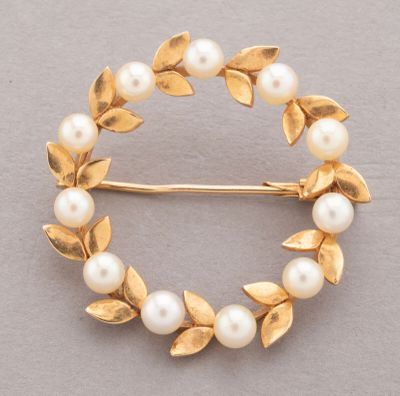 a close up of a brooch with pearls and leaves