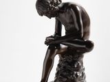 a statue of a man sitting on a rock with his head in his hands