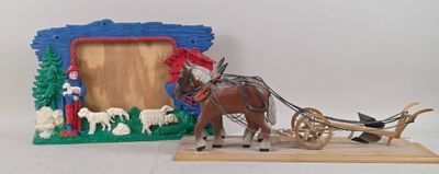 a toy horse pulling a sleigh with a picture frame in the background