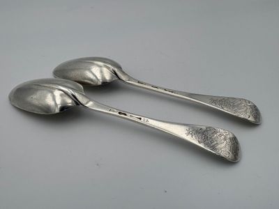 deux cuillères en argent posées sur une table l'une à côté de l'autre