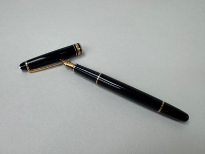 a black pen sitting on top of a white table next to a black ballpoint pen