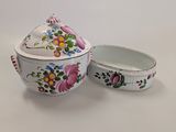 a white bowl with a lid and a bowl with flowers on it